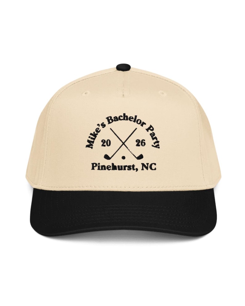 May include: A beige and black baseball cap with the text "Mike's Bachelor Party 2026 Pinehurst, NC" in black. The design includes crossed golf clubs and a golf ball.