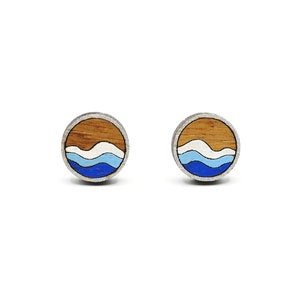 May include: A pair of wooden earrings featuring a blue and white wave design on a brown background.