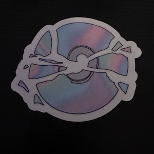 May include: A sticker of a broken compact disc with a holographic iridescent design.