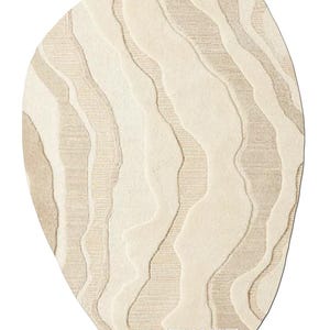 May include: An oval rug in a cream colour with a wavy, textured pattern. The rug has a subtle beige and cream colour scheme.