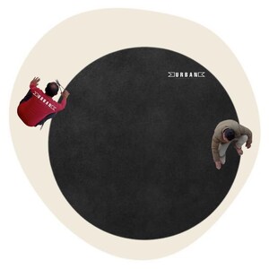 May include: Overhead view of a large, black circular rug with a cream border. Two people are positioned on either side of the rug. The word "URBAN" is printed in white on the rug.