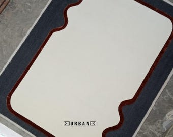 May include: A white rug with a dark blue and burgundy border. The border has a wavy, organic shape. The rug has the text "URBAN" in the center.