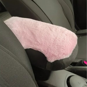 Puede incluir: Funda para reposabrazos de coche de piel sintética rosa. La funda es suave y mullida, y se ajusta al reposabrazos de un asiento de coche.