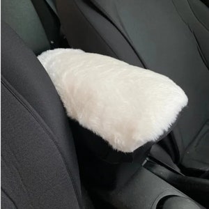 May include: White faux fur car armrest cover. The cover is soft and plush, and it can be used to protect the armrest from wear and tear.