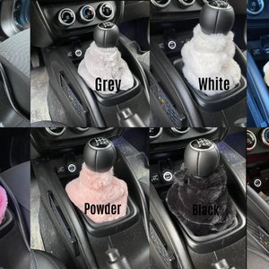 May include: Eight different coloured faux fur gear shift covers for a car. The colours are beige, grey, white, brown, pink, powder, black, and red.