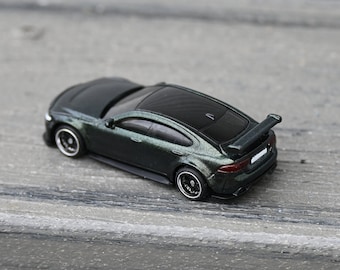 May include: A dark green die-cast toy car with a black spoiler and black wheels. The car is a sedan with a black interior and a black rear window.