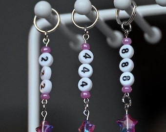 May include: Three keychains with pink and white beads and a star charm. The beads have the numbers 222, 444, and 888 printed on them.