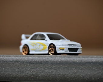 May include: A white toy car with gold wheels and yellow accents. The car has a spoiler and a detailed front end.