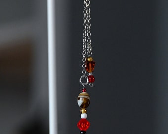 May include: A silver charm with a bell, red, white, and brown beads, and a silver chain attached to a silver key ring.