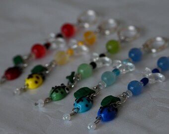 May include: Six colorful ladybug charms with clear beads and silver chain. Each charm features a ladybug with a different color and a green leaf.