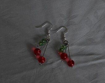 May include: A pair of silver dangle earrings with red and green glass beads. The beads are shaped like cherries with green leaves.