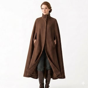 May include: A brown wool cape with a high collar and pockets. The cape is knee-length and has a classic design. The model is wearing dark pants and brown boots. The cape is a versatile outerwear piece.