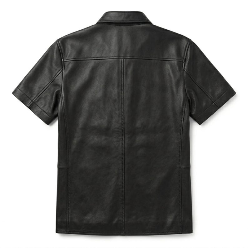 Puede incluir: Camisa negra de cuero de manga corta con cuello cl&aacute;sico. La camisa tiene una botonadura frontal y un corte entallado. La parte trasera de la camisa tiene un canes&uacute; y costuras verticales. Una prenda elegante y vers&aacute;til.