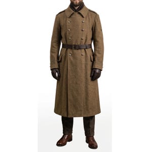 Puede incluir: Un abrigo largo de lana verde oliva con diseño de doble botonadura, cinturón de cuero marrón y guantes marrón oscuro. El abrigo tiene un estilo militar clásico con detalles de botones y un corte entallado, ideal para el frío.