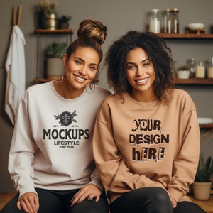 May include: Two women wearing sweatshirts. The woman on the left is wearing a white sweatshirt with a black logo that says "EST. 2021 MOCKUPS LIFESTYLE JUNCTION". The woman on the right is wearing a brown sweatshirt with the text "YOUR DESIGN HERE" in black.