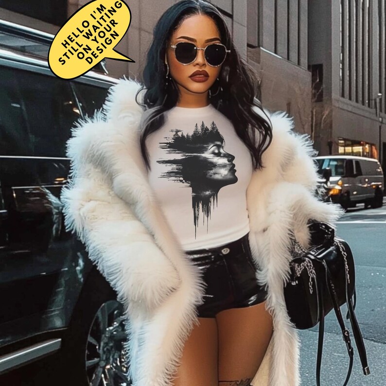 May include: A woman wearing a white t-shirt with a black and white graphic design of a woman's face with trees in the background. She is wearing a white fur coat and black shorts. The text "HELLO I'M STILL WAITING ON YOUR DESIGN" is in a yellow speech bubble.