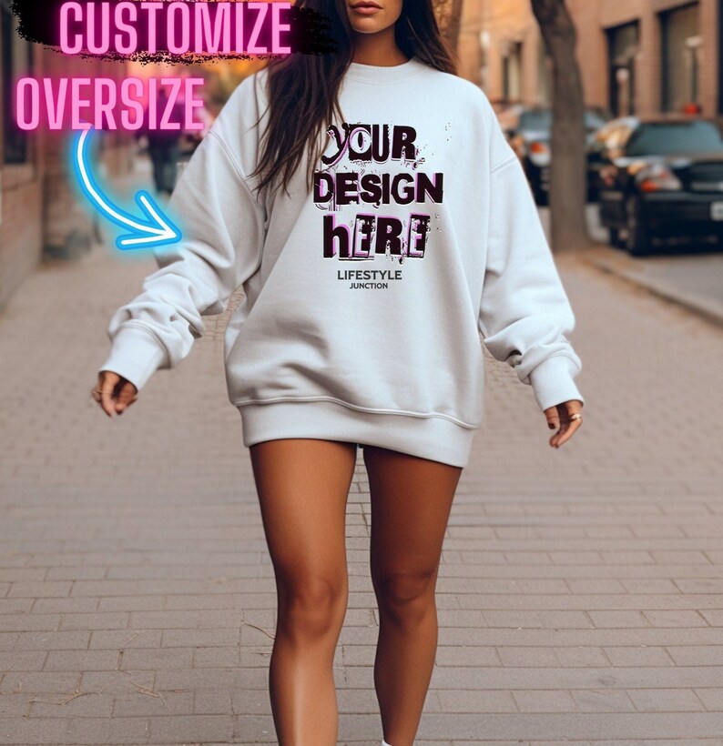 Pode incluir: Uma camiseta branca oversized com o texto "YOUR DESIGN here" em letras rosa e pretas. O texto "LIFESTYLE JUNCTION" &eacute; impresso em preto abaixo do design.