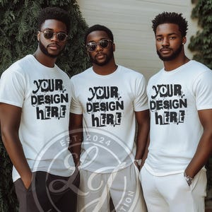 Könnte beinhalten: Drei weiße T-Shirts mit dem Text "Your Design Here" in Schwarz bedruckt. Die Shirts werden von drei Personen getragen, die vor einem grünen Busch stehen.