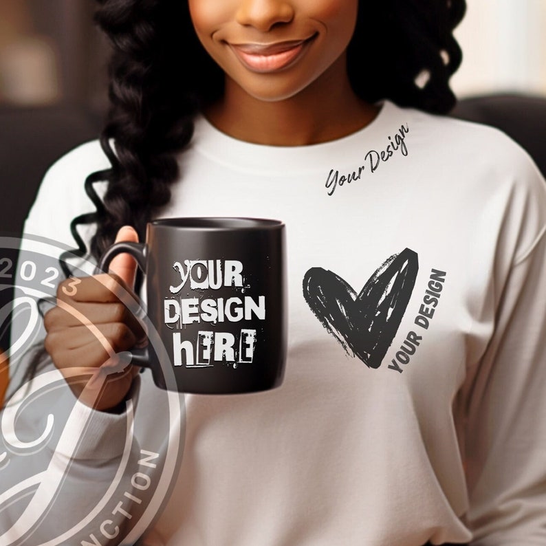 May include: A black ceramic mug with a white design that says "YOUR DESIGN HERE". The mug is being held by a person wearing a white shirt with a black heart and the text "YOUR DESIGN" on it.