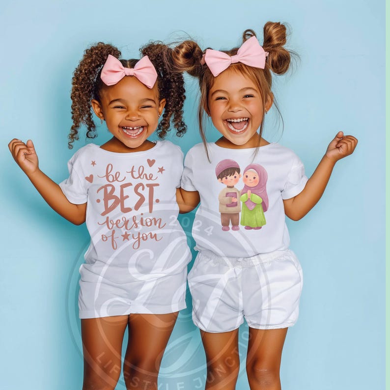 Puede incluir: Dos ni&ntilde;os peque&ntilde;os con camisetas blancas con dise&ntilde;os diferentes. La ni&ntilde;a de la izquierda tiene un lazo rosa en el pelo y su camiseta dice "S&eacute; la mejor versi&oacute;n de ti". La ni&ntilde;a de la derecha tiene un lazo rosa en el pelo y su camiseta tiene una ilustraci&oacute;n de dibujos animados de un ni&ntilde;o y una ni&ntilde;a sosteniendo un libro.