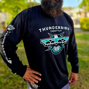 Puede incluir: Una camiseta negra de manga larga con un gráfico de águila turquesa y blanco y el texto "THUNDERBIRD THROTTLE".