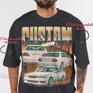May include: Black t-shirt featuring a graphic of three white cars with the word "CUSTOM AUTO" in gold and white. The shirt is worn by a person wearing a blue beanie.