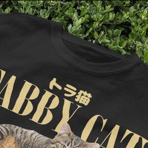 May include: Black t-shirt with a gold tabby cat graphic and the text "Tabby Cat" and "タビー猫" in Japanese.