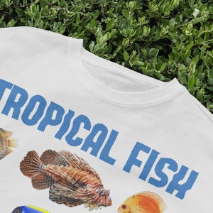 May include: White t-shirt with a blue graphic that says "TROPICAL FISH". The graphic also includes images of colorful tropical fish.