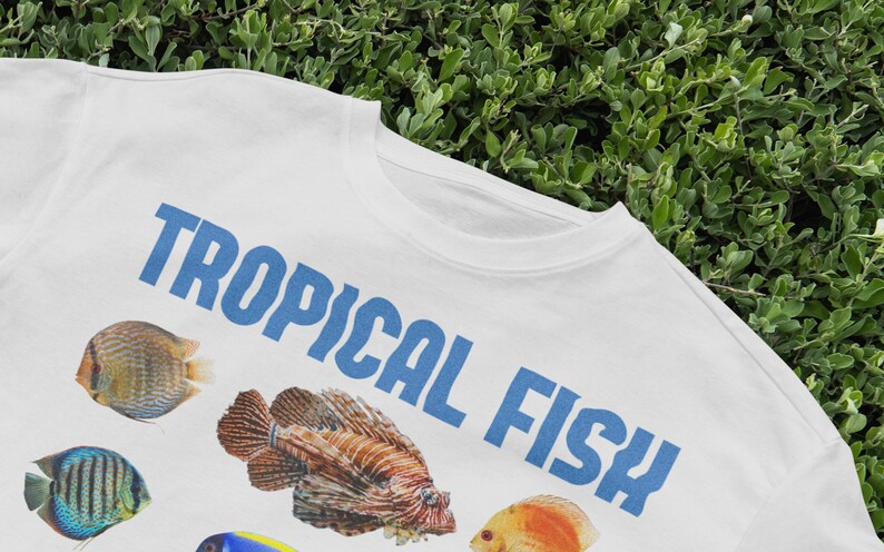 May include: White t-shirt with a blue graphic that says "TROPICAL FISH". The graphic also includes images of colorful tropical fish.