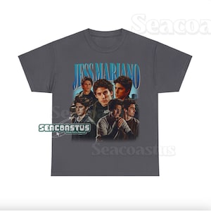 May include: A gray t-shirt with a vintage-style graphic of Jess Mariano from the TV show Gilmore Girls. The graphic features a collage of images of Jess Mariano, with the text "Jess Mariano" in a blue and white font.