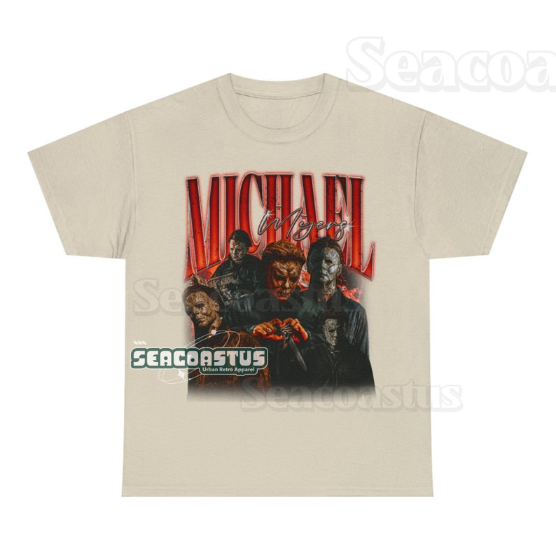 May include: A beige t-shirt with a graphic print of Michael Myers from the Halloween franchise. The graphic features multiple images of Michael Myers in different poses, with the text "MICHAEL MYERS" in red letters above the images. The text "SEACOASTUS Urban Retro Apparel" is printed in green letters below the graphic.