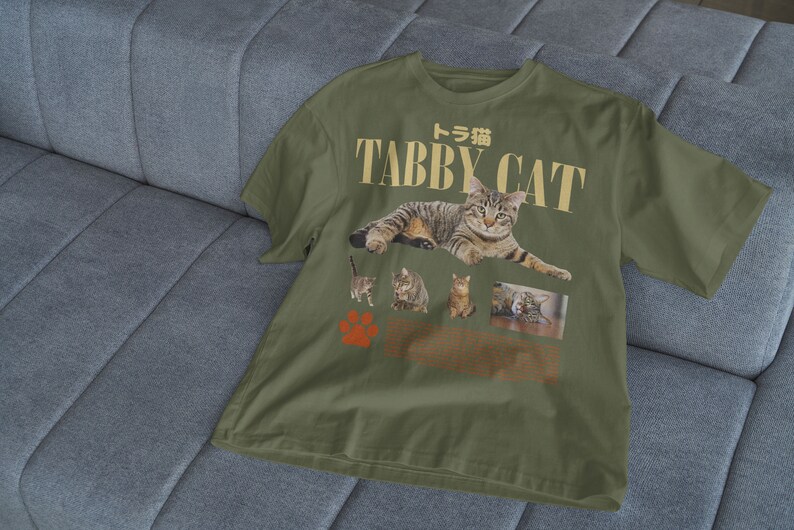 May include: A green t-shirt with a graphic print of tabby cats. The text "Tabby Cat" is printed in gold letters with the Japanese word for tabby cat above it.