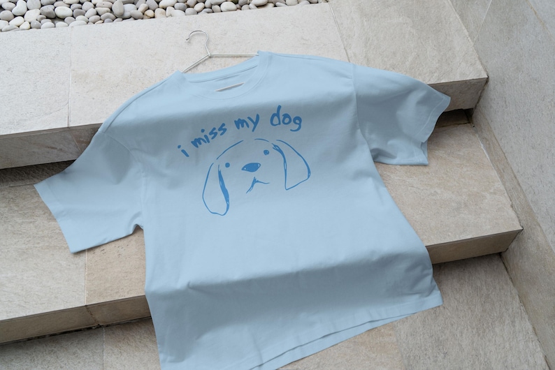 May include: A light blue t-shirt with the text "i miss my dog" and a simple line drawing of a dog's head.