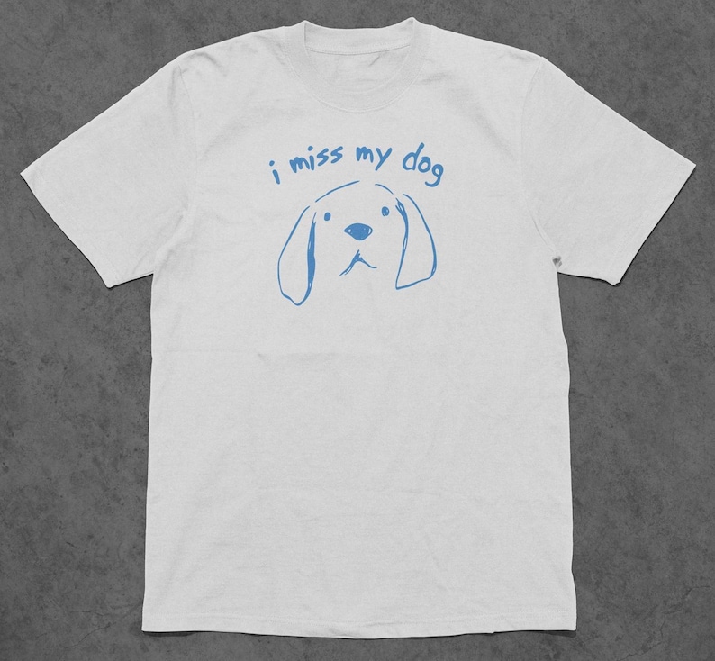 May include: White t-shirt with blue text that says "i miss my dog" and a simple blue drawing of a dog's head.