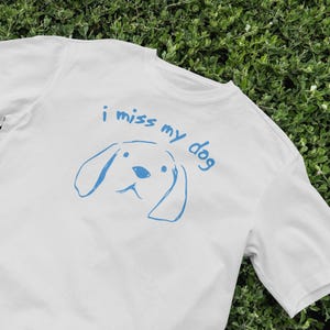 May include: White t-shirt with a blue graphic of a dog and the text "i miss my dog"