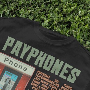 May include: Black t-shirt with the word "PAYPHONES" in green, and a graphic of a red payphone booth. The word "Phone" is also visible. The shirt has a vintage, retro aesthetic.