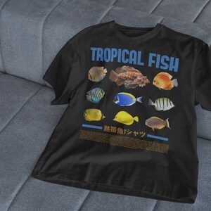 May include: Black t-shirt with a graphic of colorful tropical fish and the text "TROPICAL FISH" in blue letters. The text "熱帯魚デザイン" is also printed on the shirt.