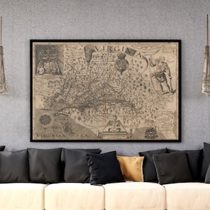 May include: A vintage map of Virginia, framed in black, hangs above a beige couch with black pillows. The map is titled "Virginia" and shows the coastline, rivers, and towns of the state. The map is dated 1606.
