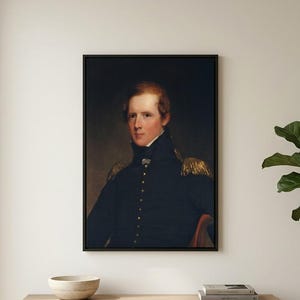 May include: A framed portrait of a man in a dark blue military uniform with gold epaulettes. The painting is set against a dark background, with the subject seated. The frame is black, and the artwork is displayed above a wooden cabinet.