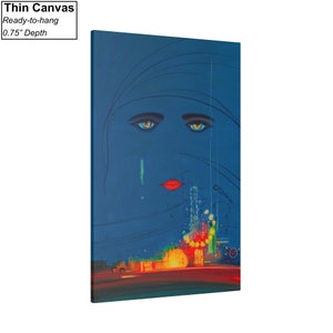 May include: A blue canvas print featuring a stylised image of a woman's face with large blue eyes and red lips. The background is a dark blue with a cityscape in the bottom half of the image.