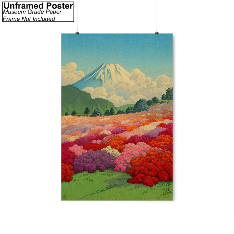 Op de afbeelding: Een vintage Japanse houtsnede die de berg Fuji op de achtergrond toont met een veld met roze, rode en paarse bloemen op de voorgrond. De lucht is blauw met witte wolken.