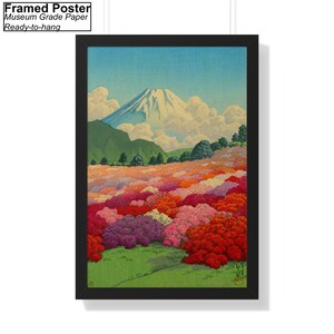 Op de afbeelding: Een ingelijste poster met een Japanse landschapsschildering van de berg Fuji met een veld vol roze, rode en witte bloemen op de voorgrond. De lucht is blauw met witte wolken.
