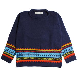 Può includere: Un maglione blu navy con girocollo e maniche lunghe. Le maniche e l'orlo inferiore presentano un colorato motivo geometrico con lama in blu, giallo, arancione e rosso. Il maglione è realizzato in morbido materiale a maglia.