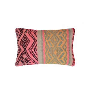 Può includere: Cuscino decorativo rettangolare con un motivo geometrico intrecciato. Il cuscino presenta un motivo a rombi rosa e neri a sinistra, una striscia grigia al centro e un motivo a rombi arancioni e grigi a destra. Un elemento d'arredo per la casa.