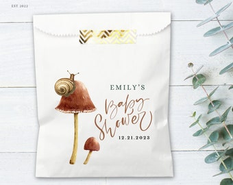 May include: White favor bag with a brown mushroom and snail design. The text "Emily's Baby Shower" and the date "12.21.2023" are printed on the bag.