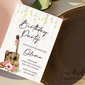 May include: A rustic-themed birthday party invitation with a watercolor illustration of a guitar, cowboy boots, and pink flowers. The text reads "Birthday Party" and "Join us in celebrating Olivia". The invitation includes the location, "The Barn, 23456 Old Town Rd, Any City, ST 34532", and RSVP information.