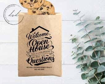 May include: A brown paper bag with a welcome to the open house sign. The sign has black text that says "Welcome to the Open House, Take a look around and ask questions". The bag also has the text "Bicana Crown | REMAX Realty 555.555.5555" printed on it.