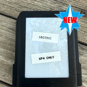May include: Black Lectric XP4 e-reader with a white screen. The device has the text "LECTRIC" and "XP4 ONLY" on the screen. A blue and white starburst graphic with the word "NEW" in red is in the upper right corner.