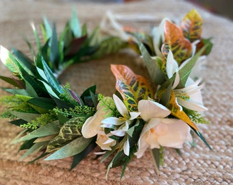 May include: A green and white floral crown with white flowers and green leaves. The crown is made of artificial flowers and leaves.