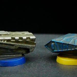 May include: Four miniature spaceships painted in different colors and styles. The spaceships are on circular bases with different colors. The spaceships are made of metal and have a weathered look.